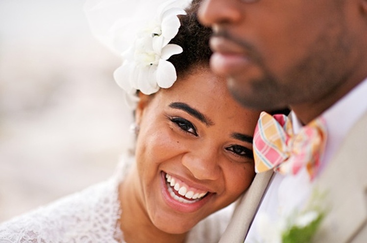 Casal, mulher sorrindo com vestido de casamento e flor na orelha