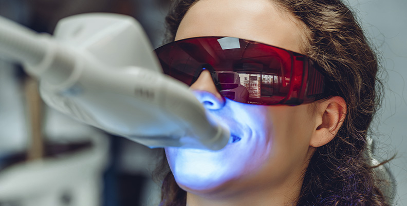 mulher realizando o procedimento de clareamento dental a laser