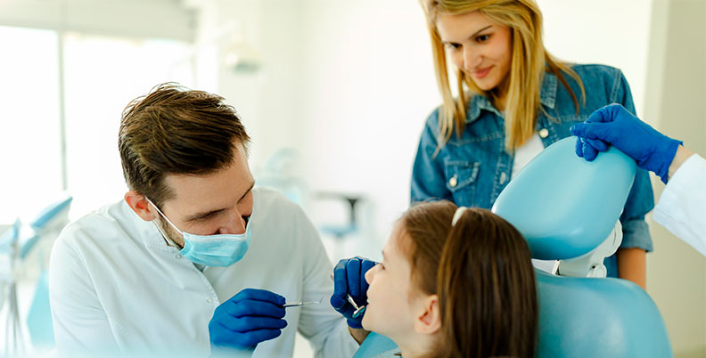 Dentista realizando uma consulta em uma paciente criança