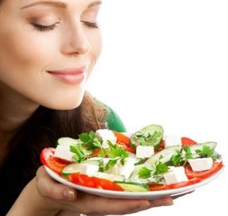 Mulher com olhos fechados sorrindo e prato de salada na mão