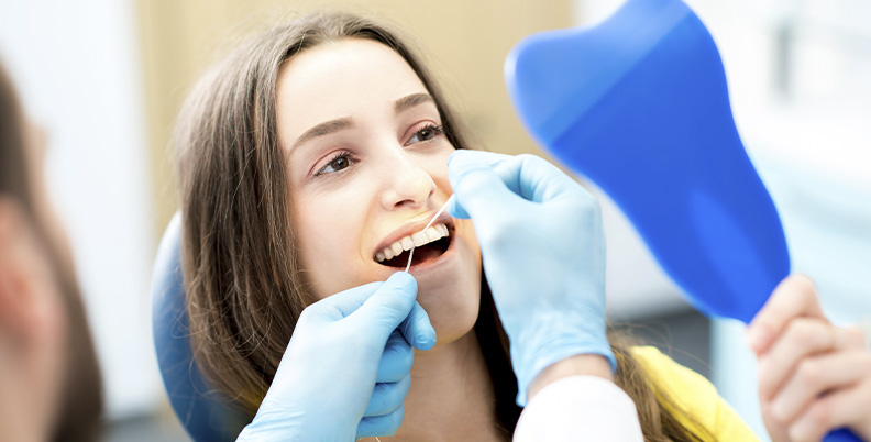 dentista passando fio dental na paciente