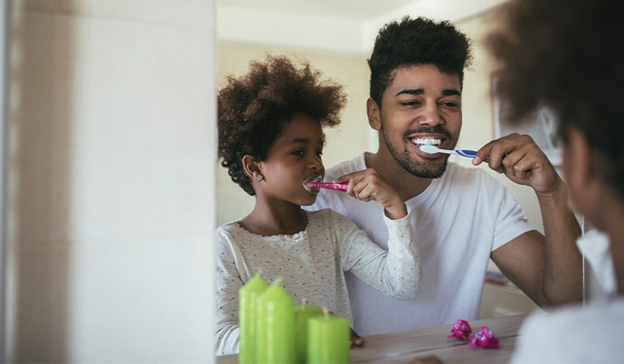 pai ensinando à sua filha como escovar os dentes