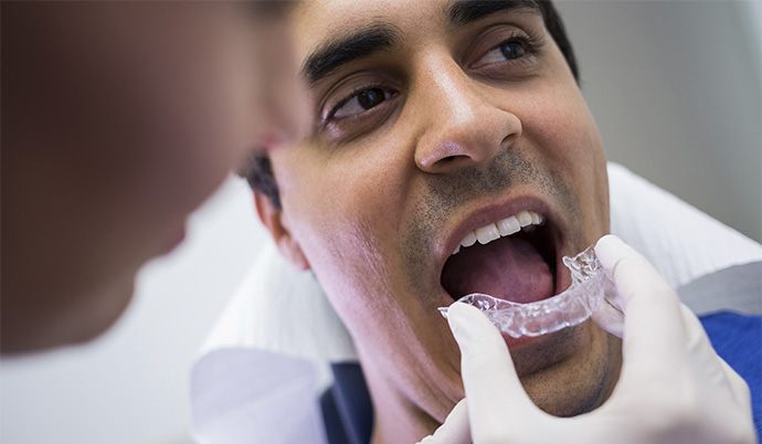 Dentista colocando um aparelho Invisalign em seu paciente.