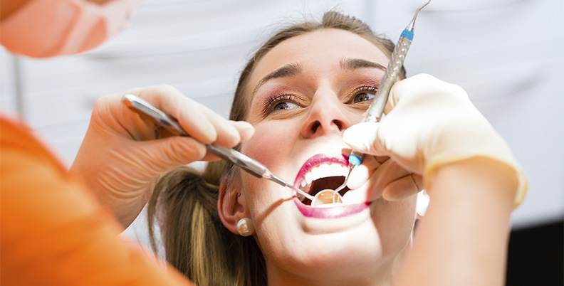 mulher no dentista realizando o processo de limpeza