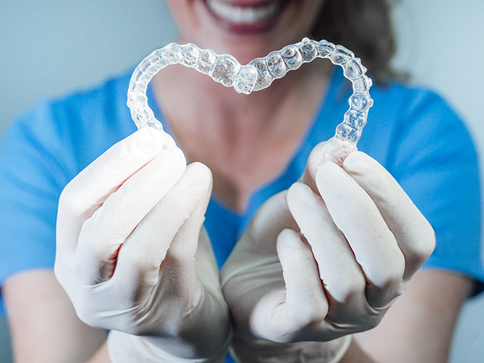 Dois alinhadores ortodônticos transparentes na mão de dentista formando um coração