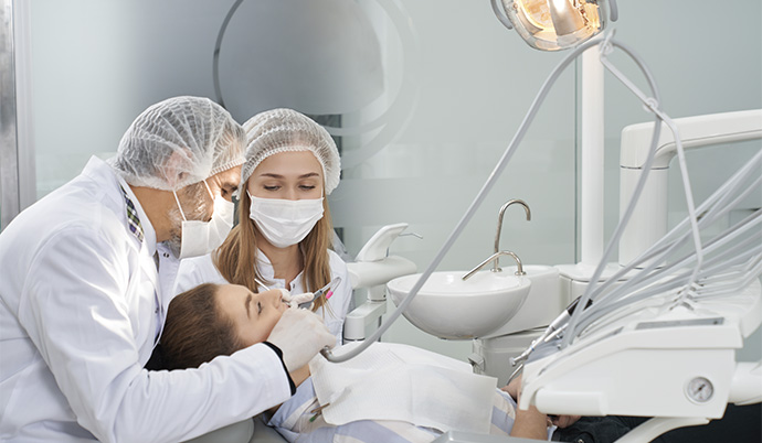 dentistas realizando procedimento odontológico em uma mulher