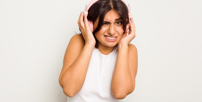 mulher com fones sentindo dor no ouvido por conta do volume alto
