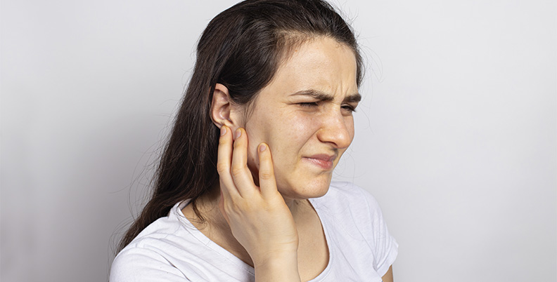 menina com dor de ouvido pressionando a mandíbula