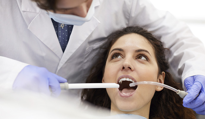 mulher com a boca aberta para que o dentista possa tratar seu dente